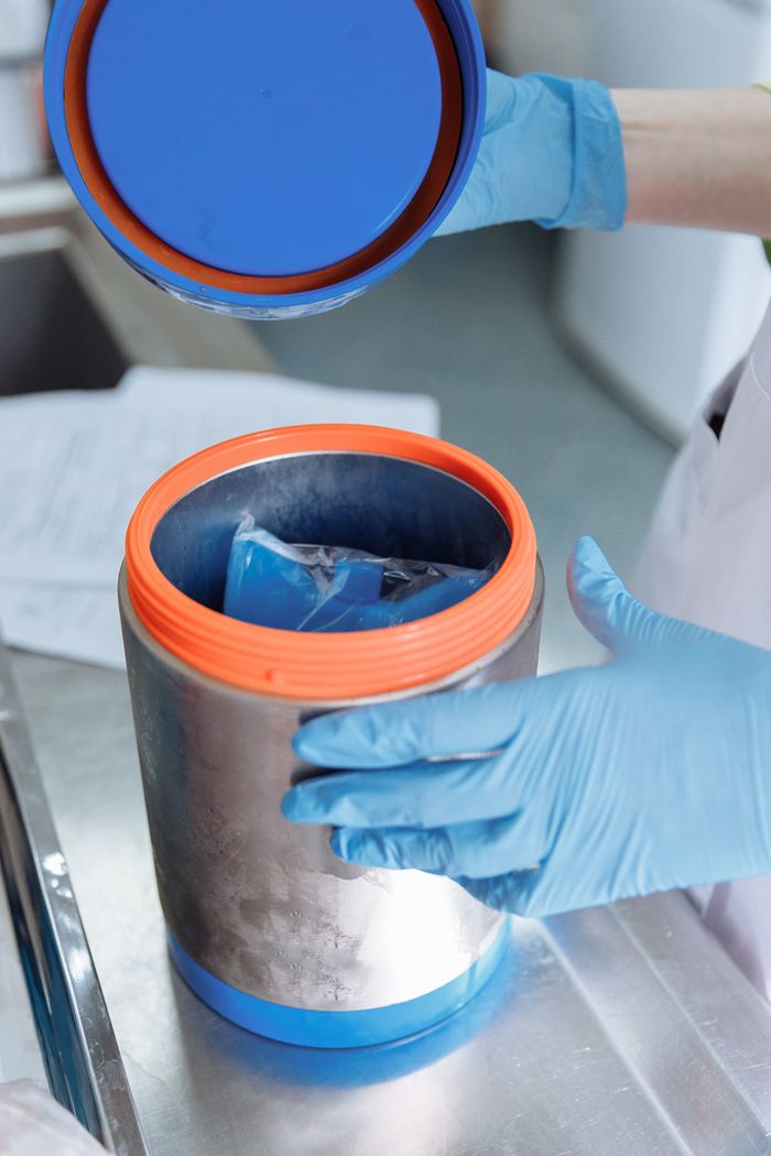 A scientist uses gloves to open a sterile container in a laboratory setting.
